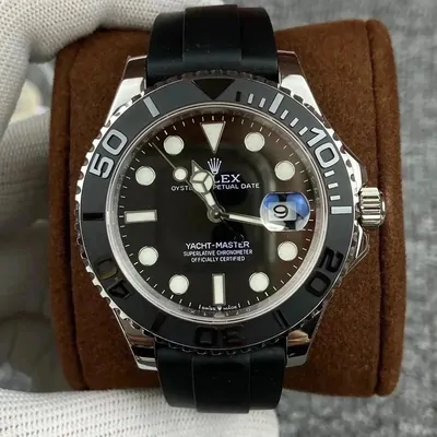 A steel dive watch with a black dial and rotating bezel on a dark rubber strap, sitting on a cushion